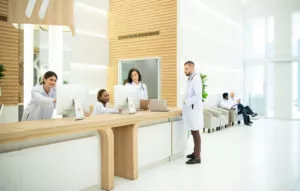 Recepção de hospital com médicos e recepcionistas conversando